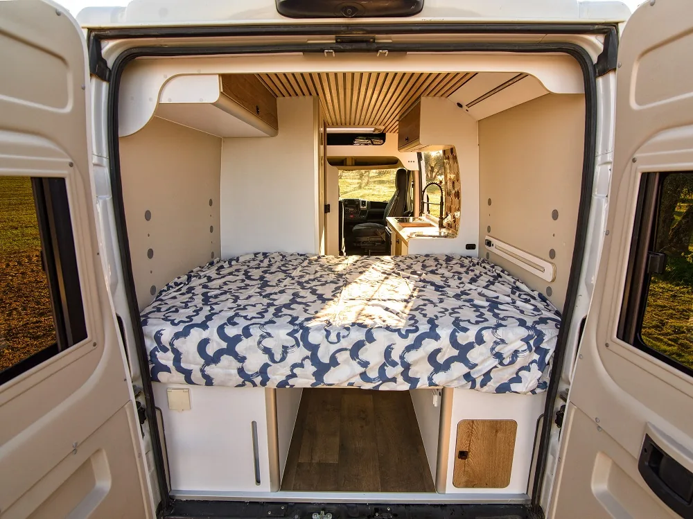 Cama trasera de una camper Alquicamper con vistas al bosque · empezamos con dos furgonetas en Madrid