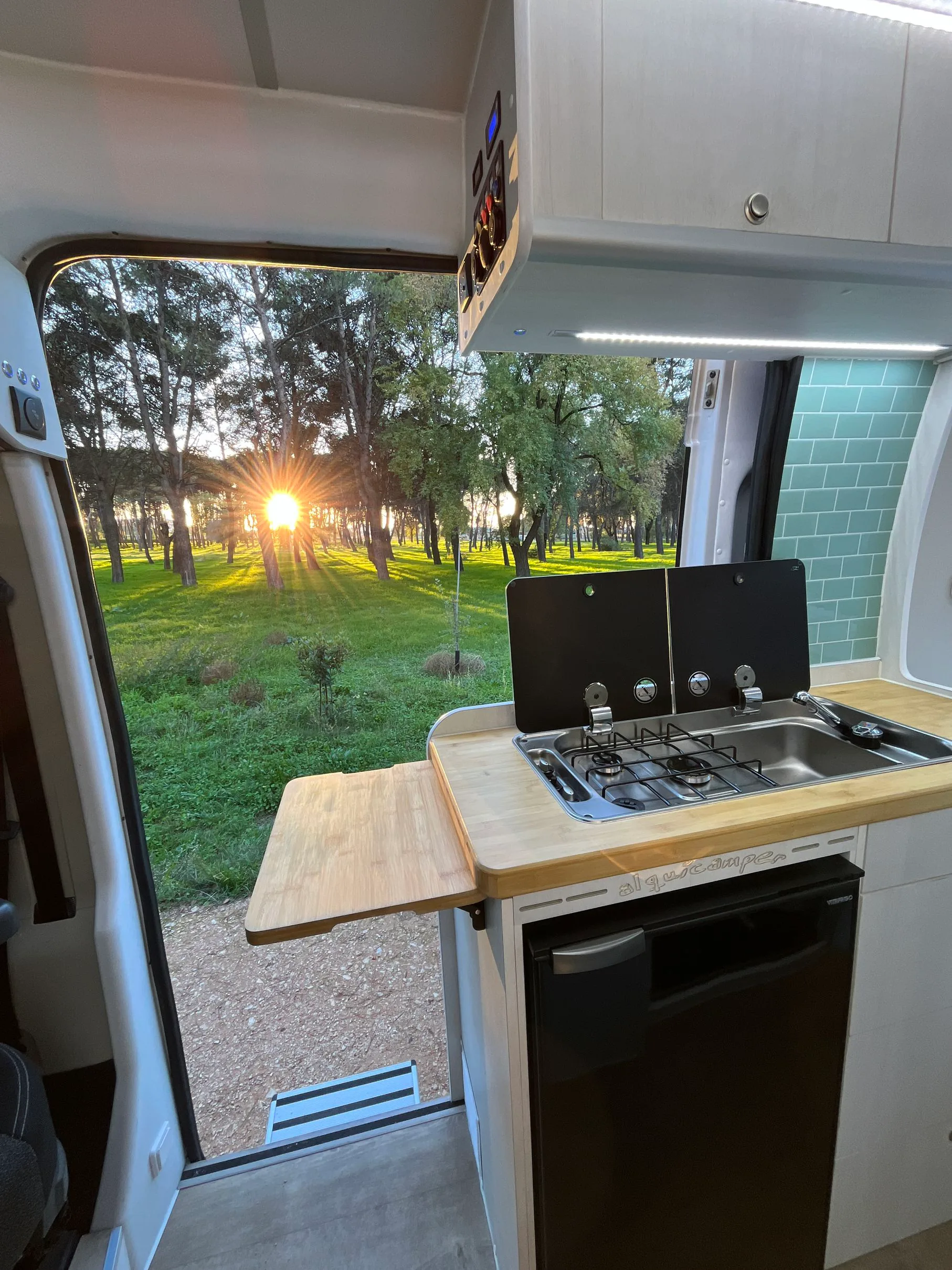 Cocina abierta de una camper Alquicamper al amanecer en un bosque · viaje en furgoneta camper