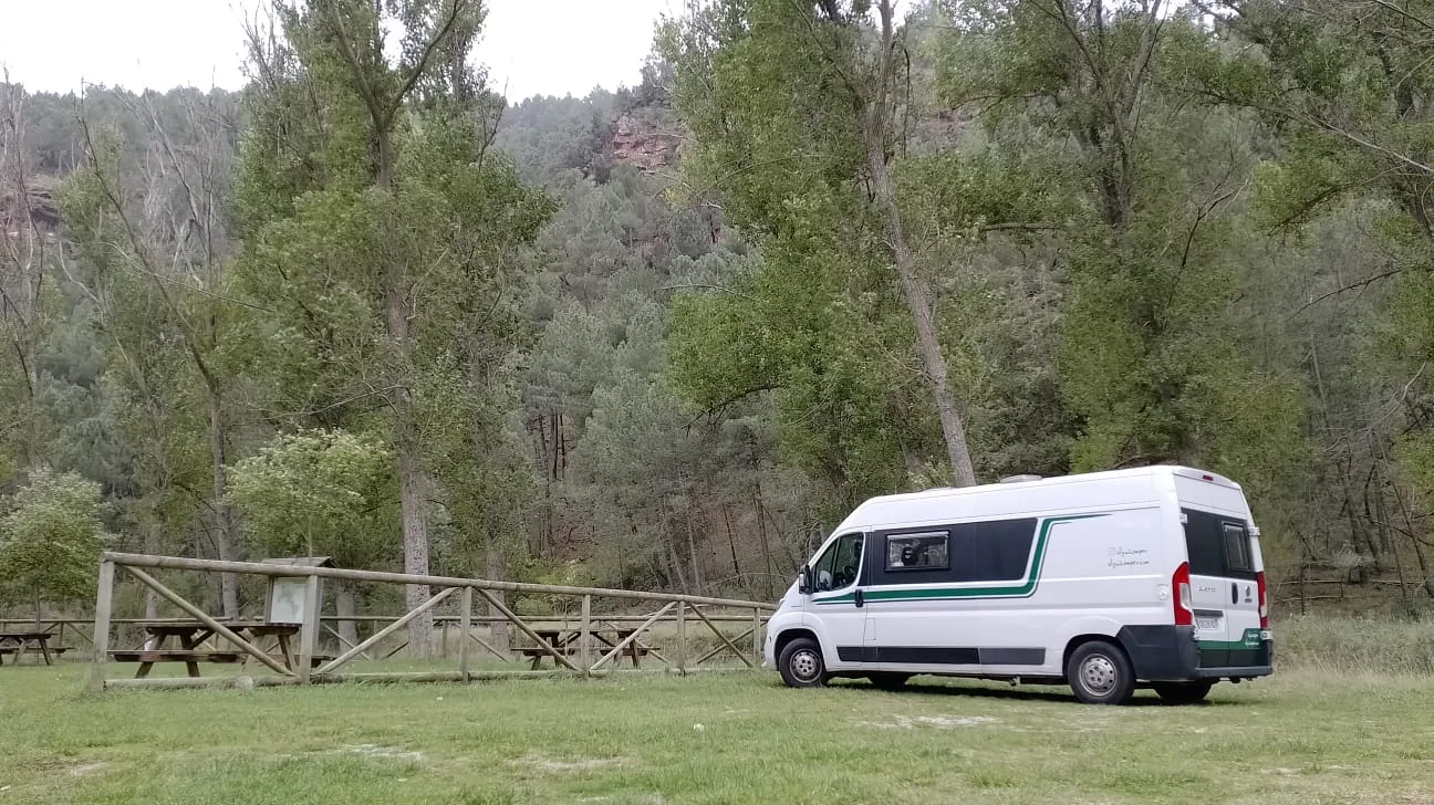 Camper Alquicamper aparcada junto a un río rodeada de árboles · alquiler de furgonetas camper en Madrid